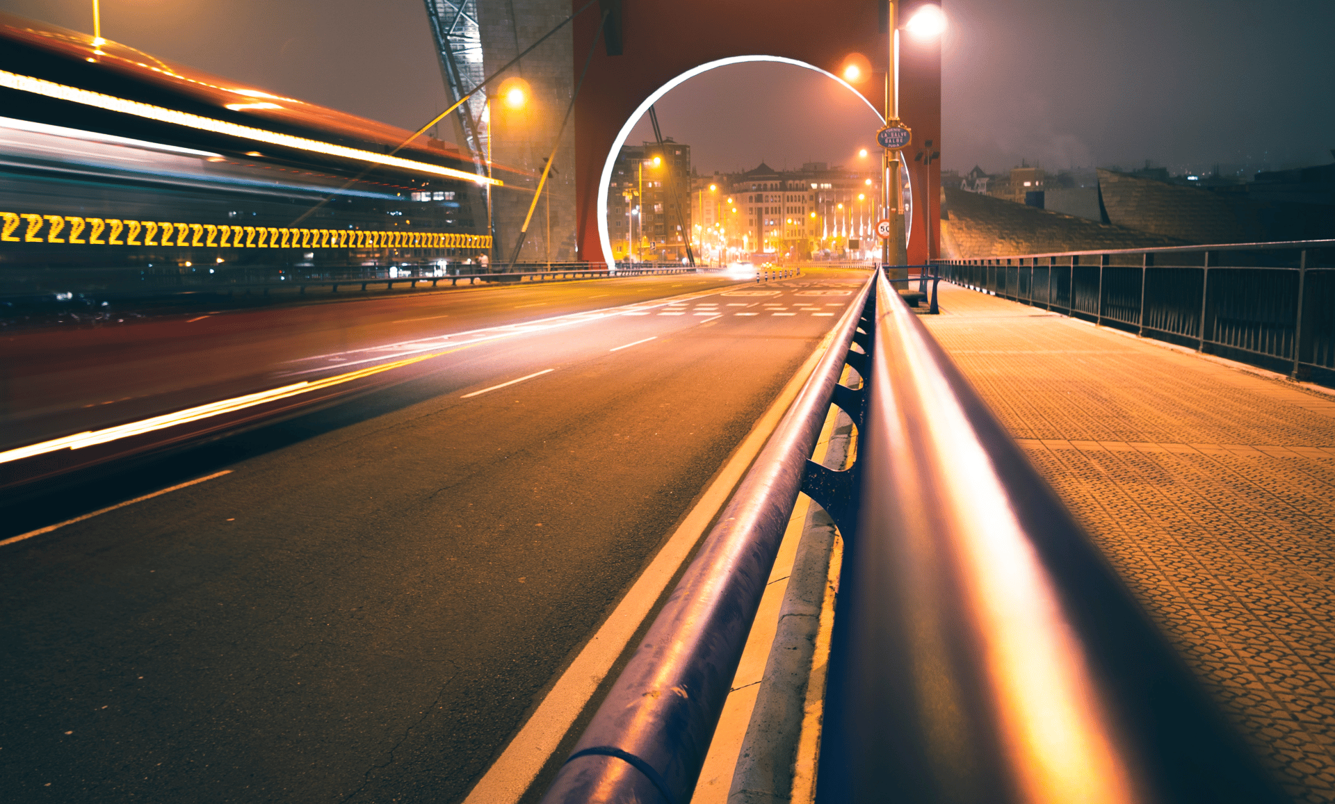 fast moving cars on a bridge at night